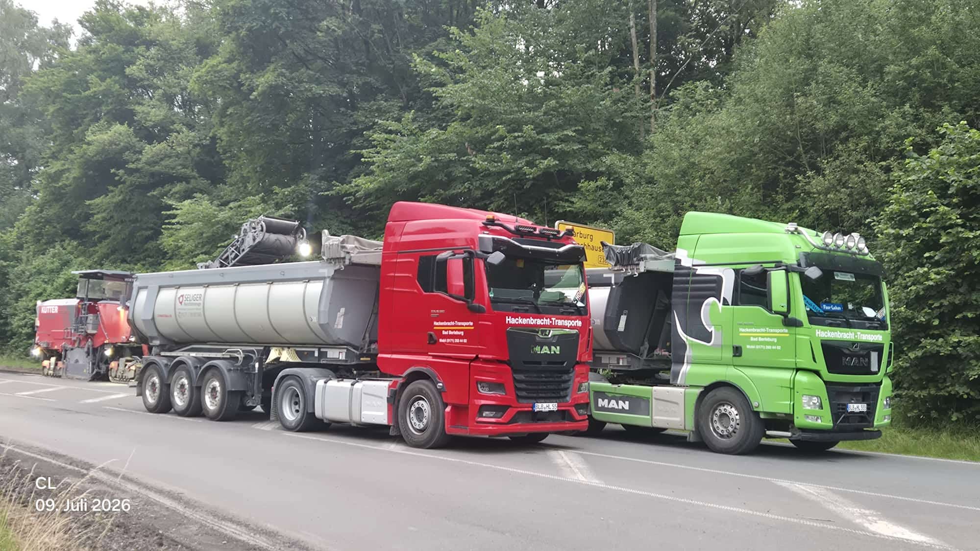 Rote und grüne MAN-Lkw von Hackenbracht-Transporte mit Aufliegern nebeneinander auf der Straße