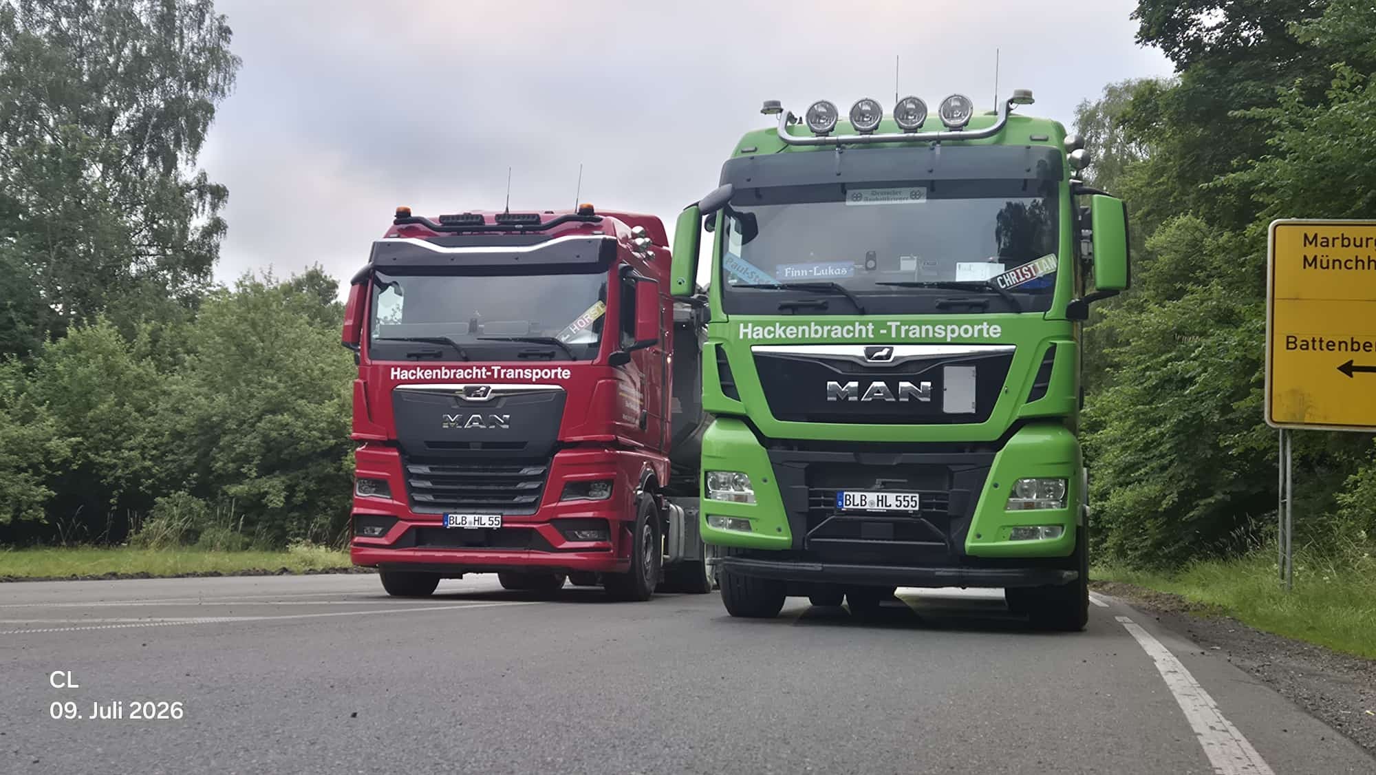 Roter und grüner MAN von Hackenbracht-Transporte nebeneinander auf der Straße