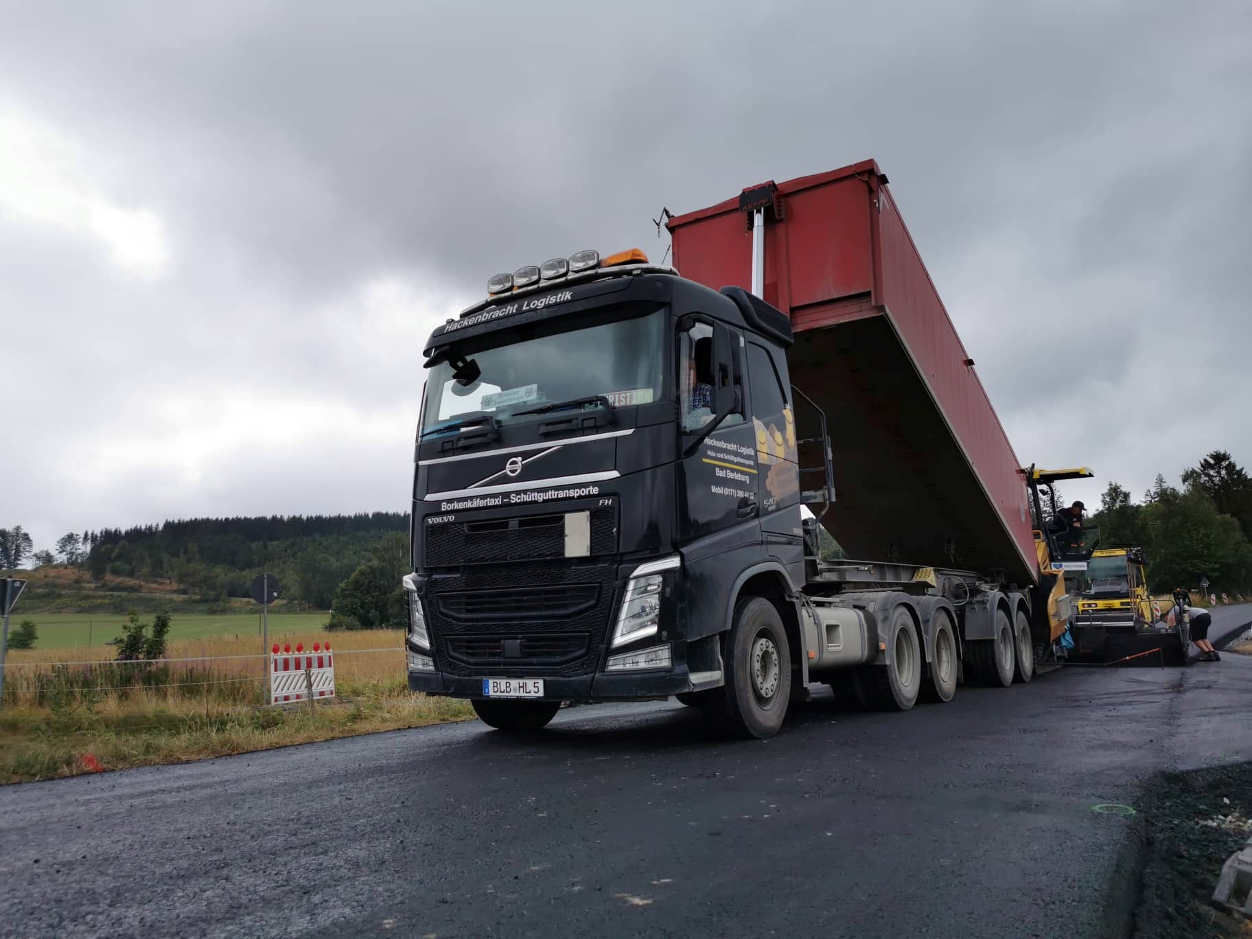 Volvo FH von Hackenbracht Logistik mit aufgestellter Kippmulde an der Baustelle